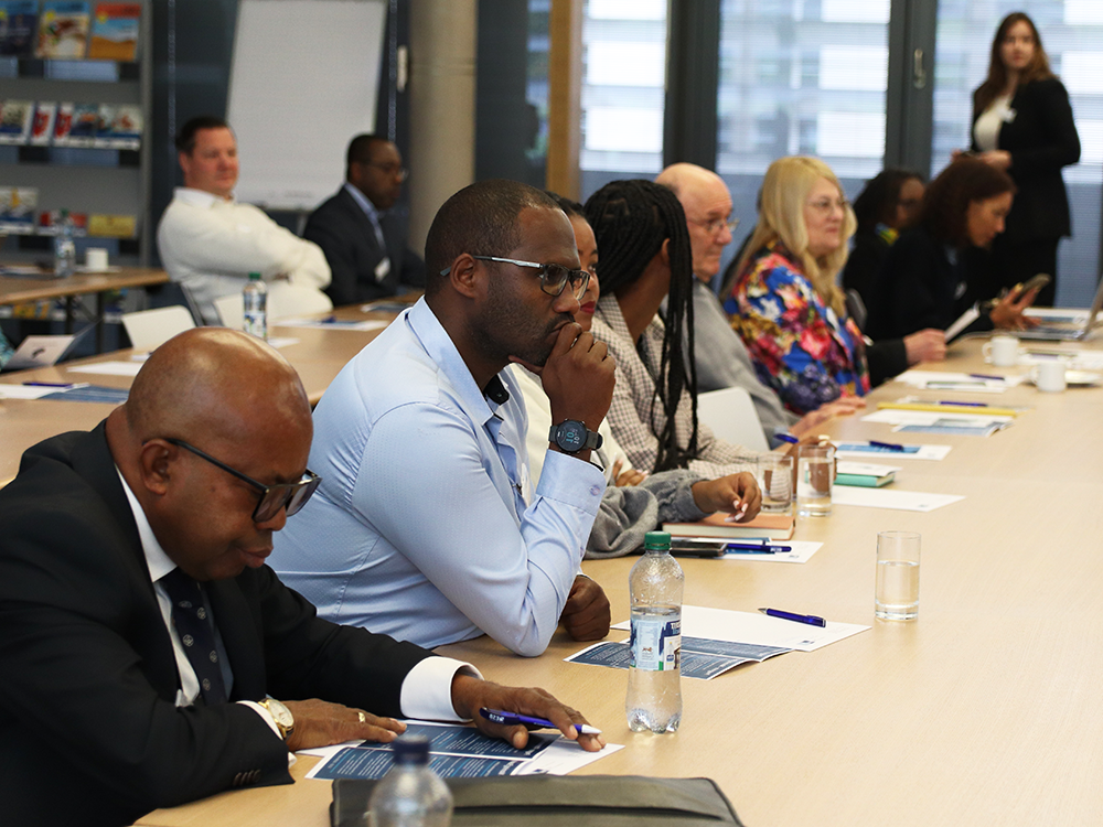 Menschen sitzen an einer langen Tischreihe mit Noitzen